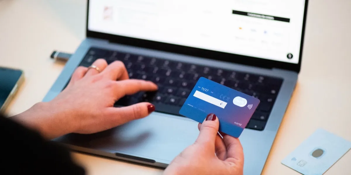 Person holding a credit card while making an online payment on a laptop